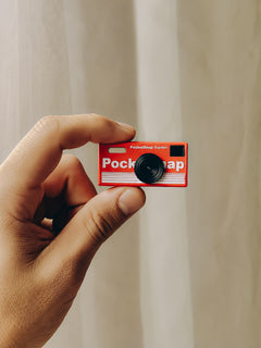 DigiSnap pocket keychain camera held in a hand, showing the front lens and flash
